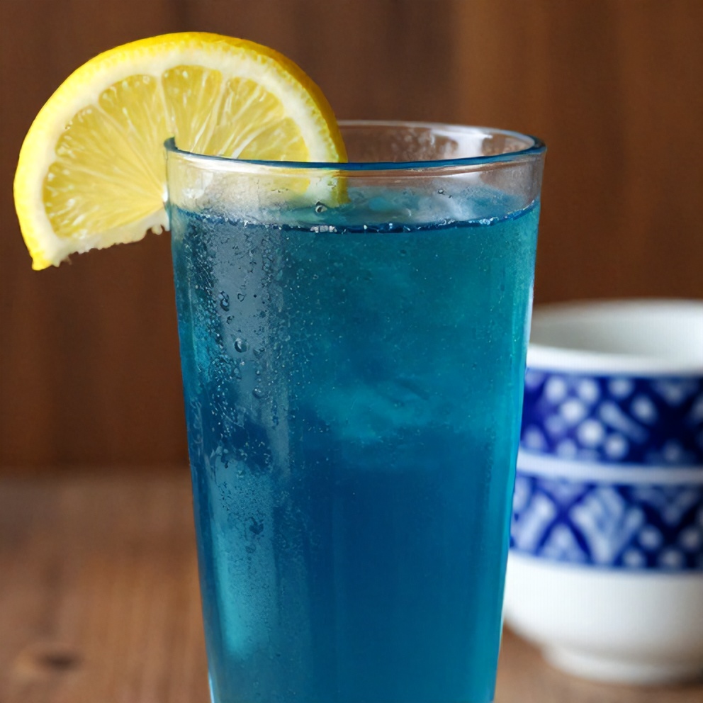 Blue spirulina juice poured into a glass with a lemon slice garnish