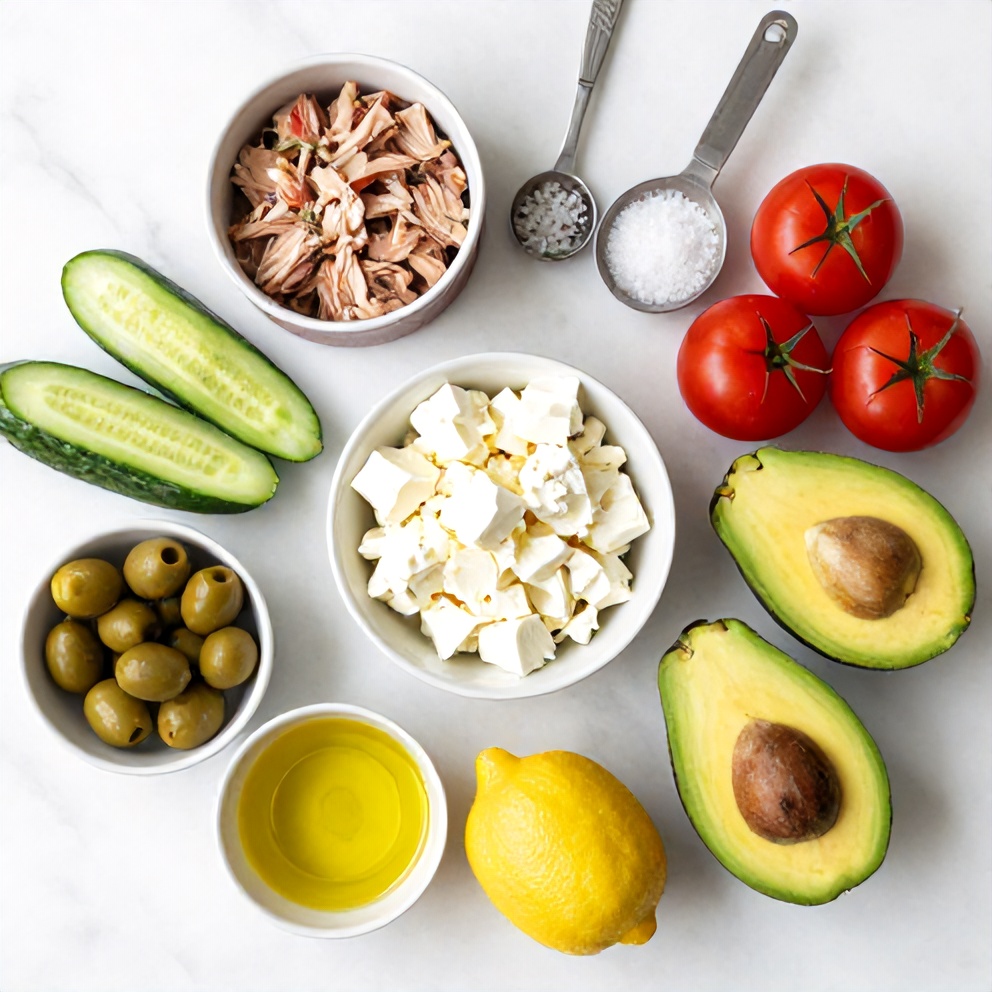 Raw ingredients for Mediterranean Tuna Salad: canned tuna, cucumbers, tomatoes, avocado, olives, feta, lemon, olive oil, salt, pepper