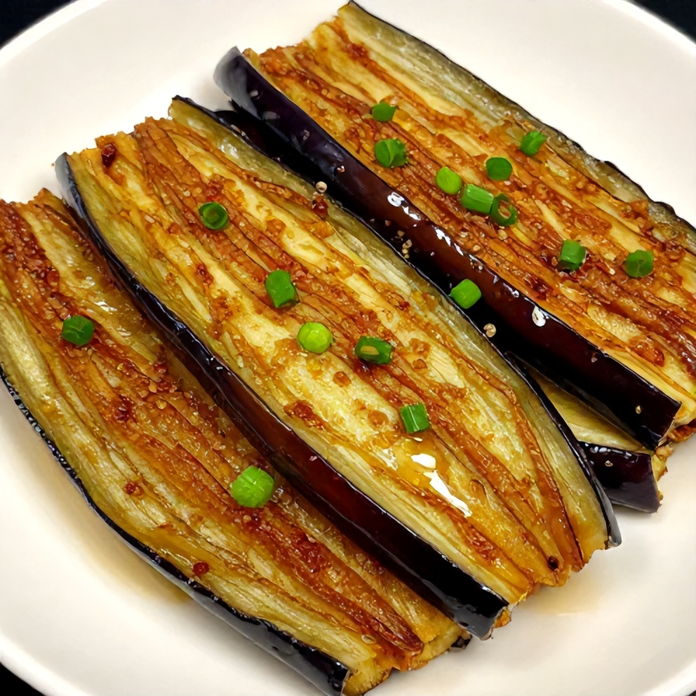 Miso glazed eggplant slices on a white plate with green onions