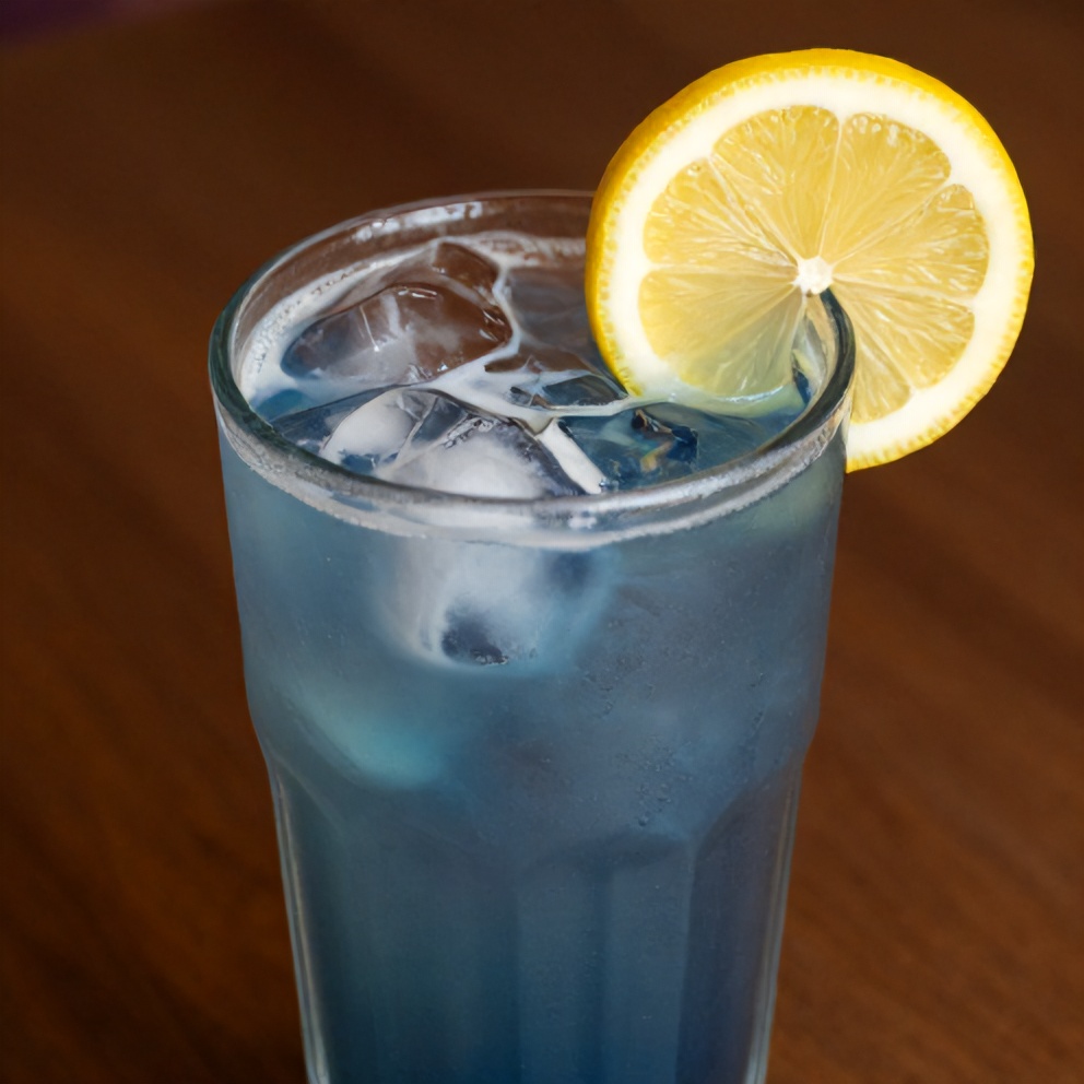 Iced butterfly pea flower tea latte with a lemon slice garnish
