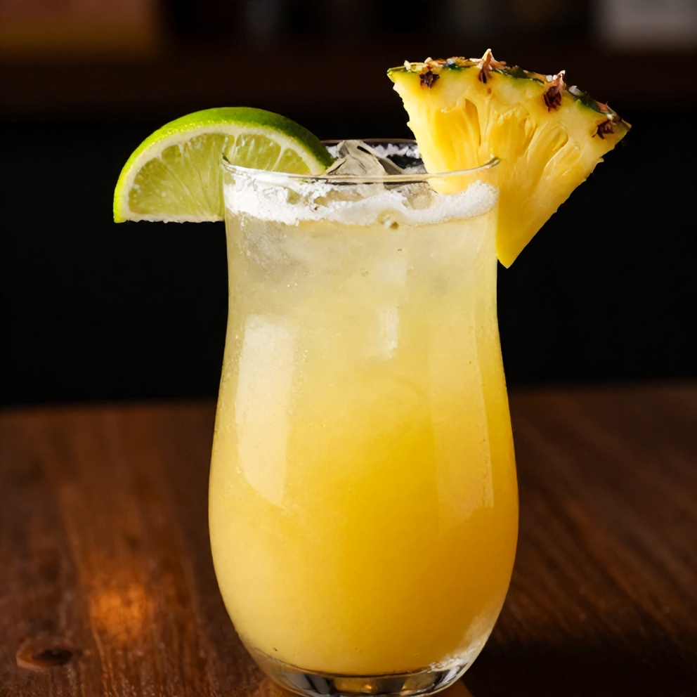 A plated serving of pineapple margarita mocktail with a lime wheel and pineapple wedge garnish